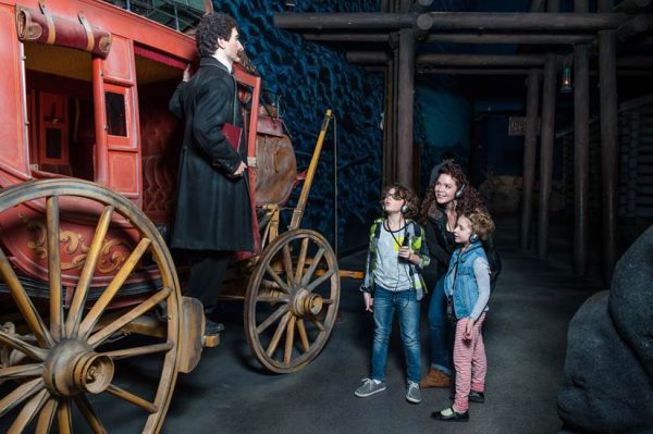 a family looking at an old carriage. 
