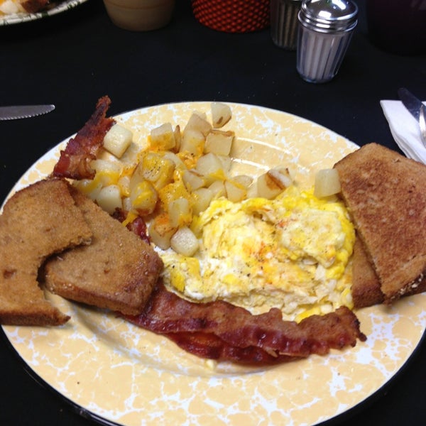 Breakfast plate of scrambled eggs, cubed potatoes, and bacon. 