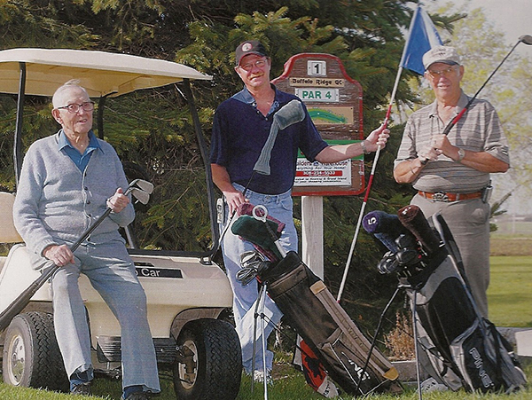 three men holding their golf clubs as they pose for a photo. 