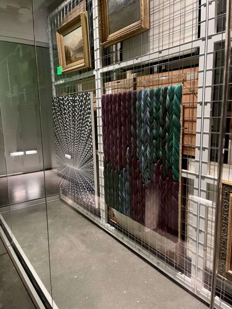 artwork of various mediums behind a glass wall.