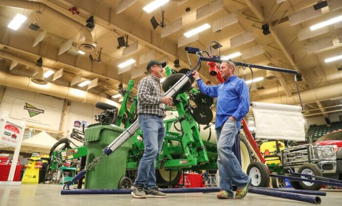 Two men talking at gateway farm expo in front of farm combine.