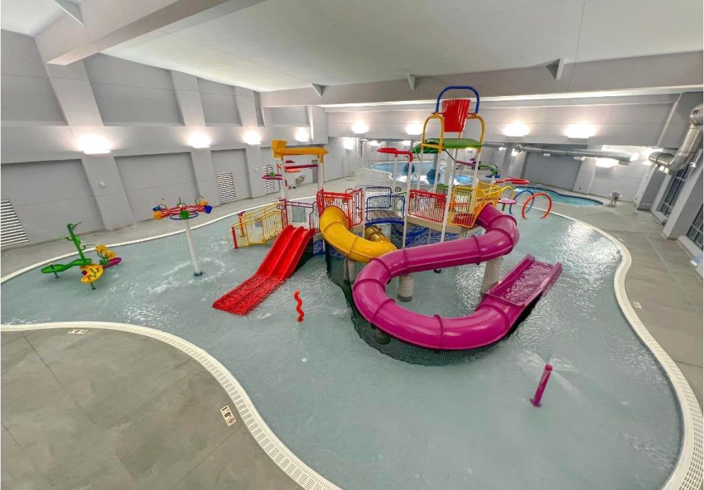 indoor irregularly shaped pool with colorful waterslides.