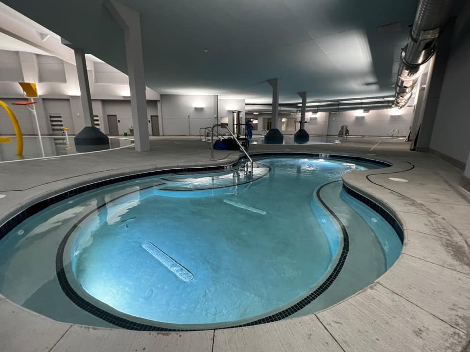 pear shaped pool with stairs with concrete edge, next to the waterslides