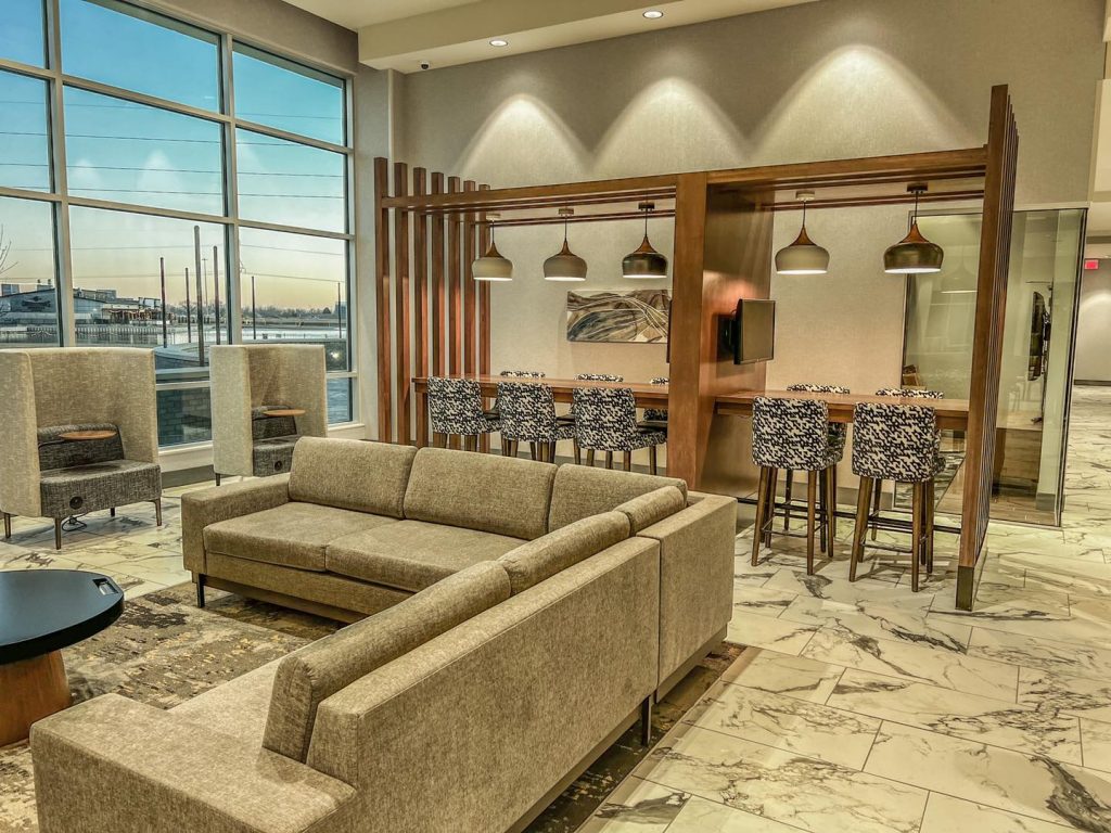 large sectional couch, hightop tables with hanging lamps overhead facing wall of windows