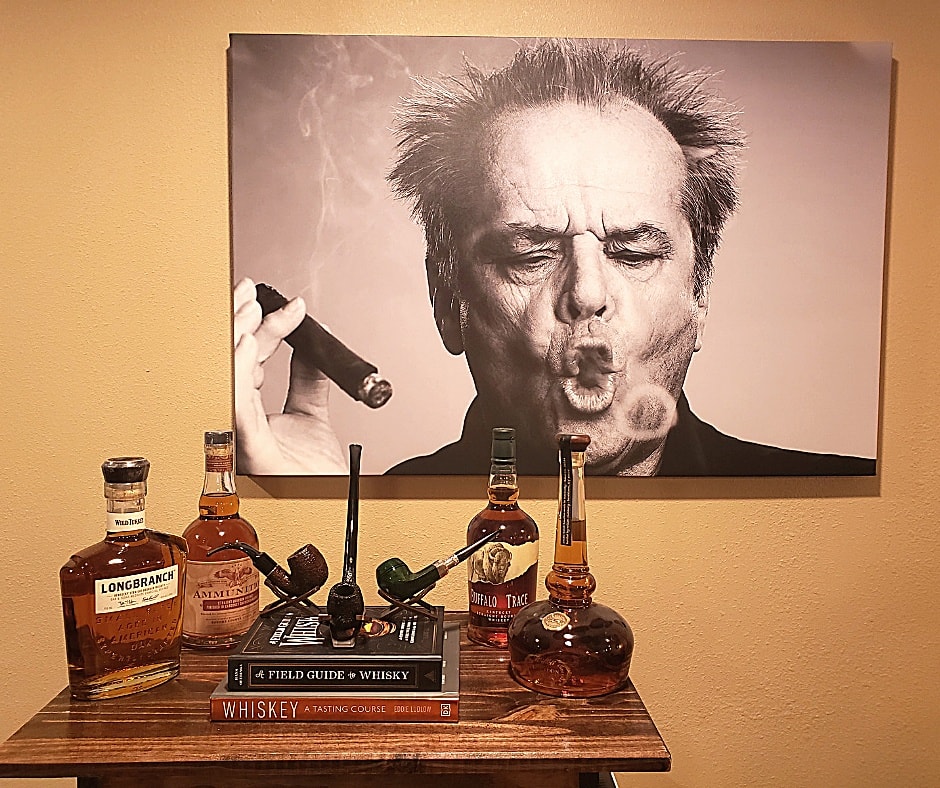 display of liquor and old fashioned cigars with photo on wall of a man smoking. 