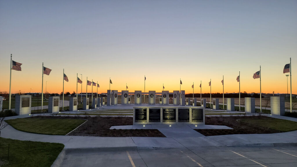 Central Nebraska veterans memorial with American flags surrounding it during sunset.