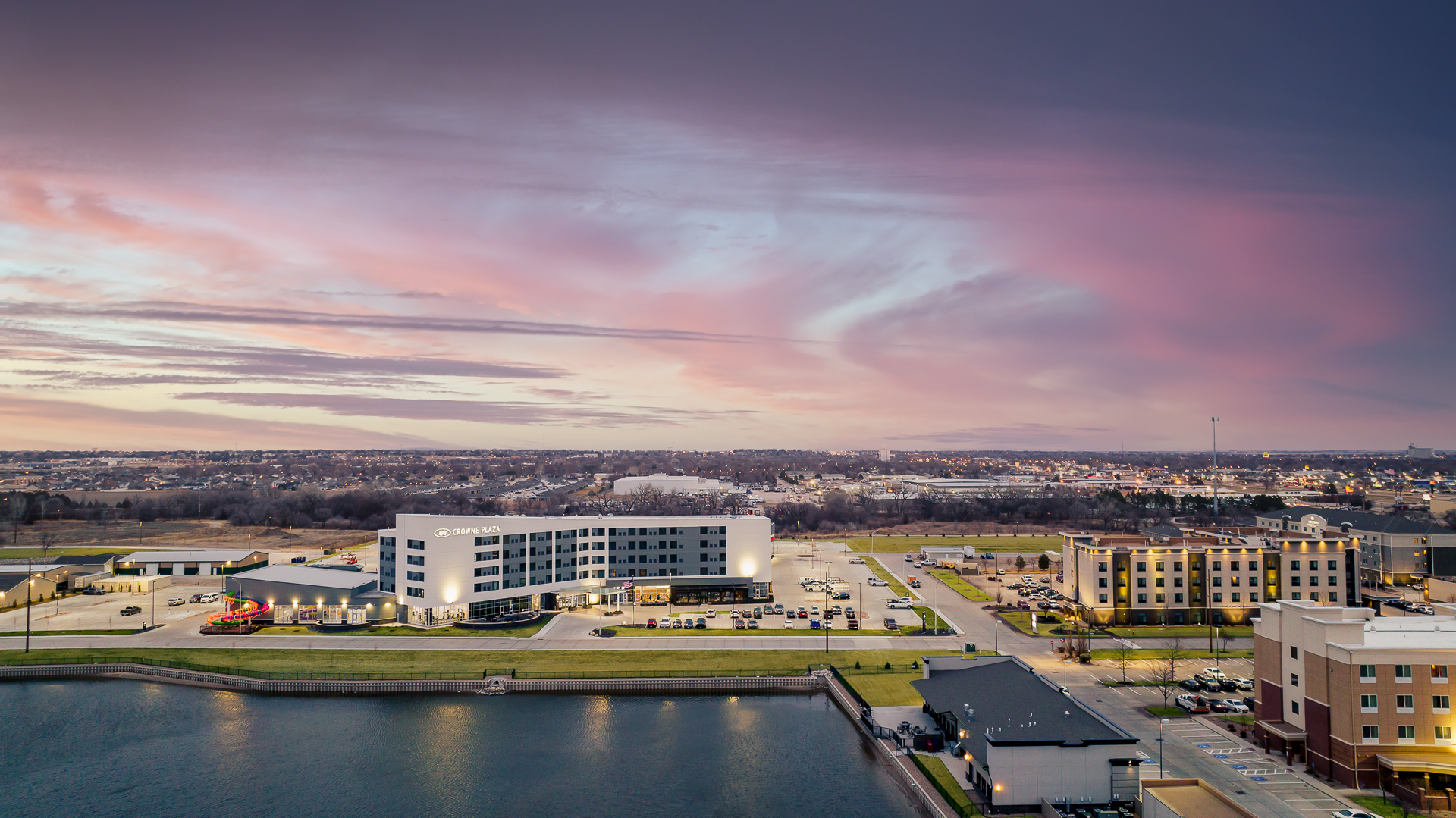 Multiple large hotel buildings by a lake during a pink and blue sunset