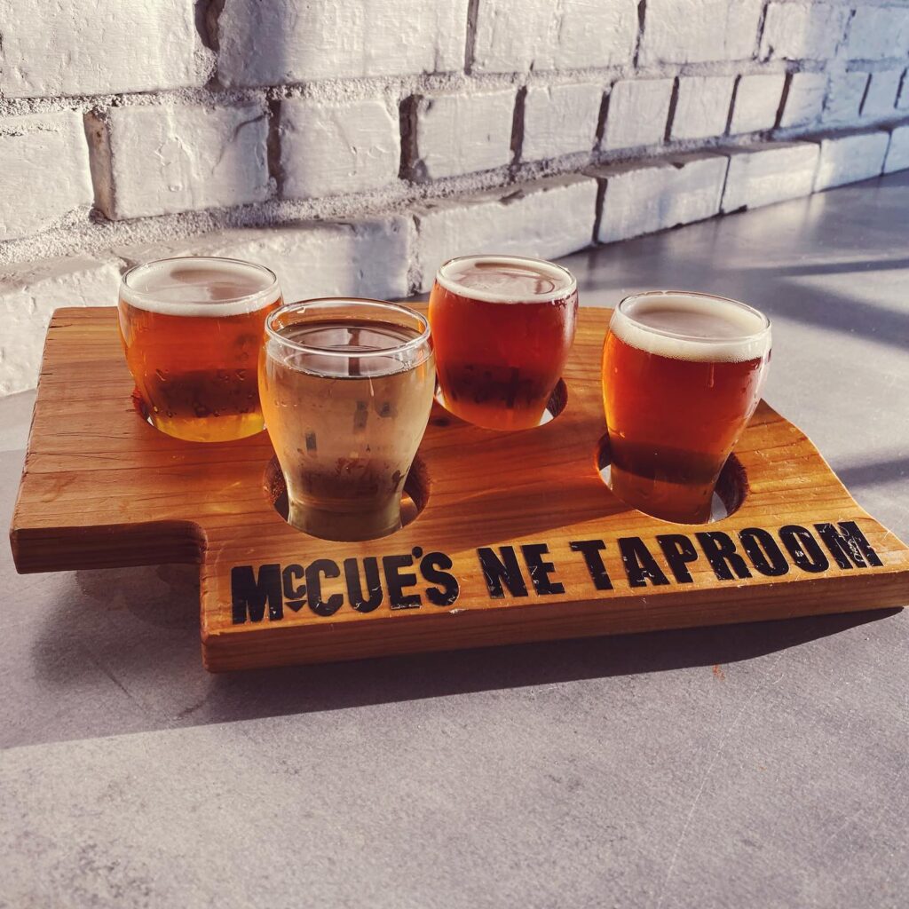Flight of beers on Nebraska shaped wood platter and McCue's NE Taproom written on it.