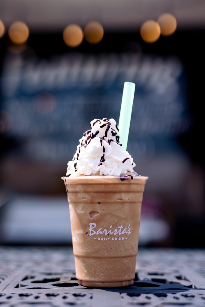 chocolate drink topped with mountain of whipped cream and chocolate sauce 
