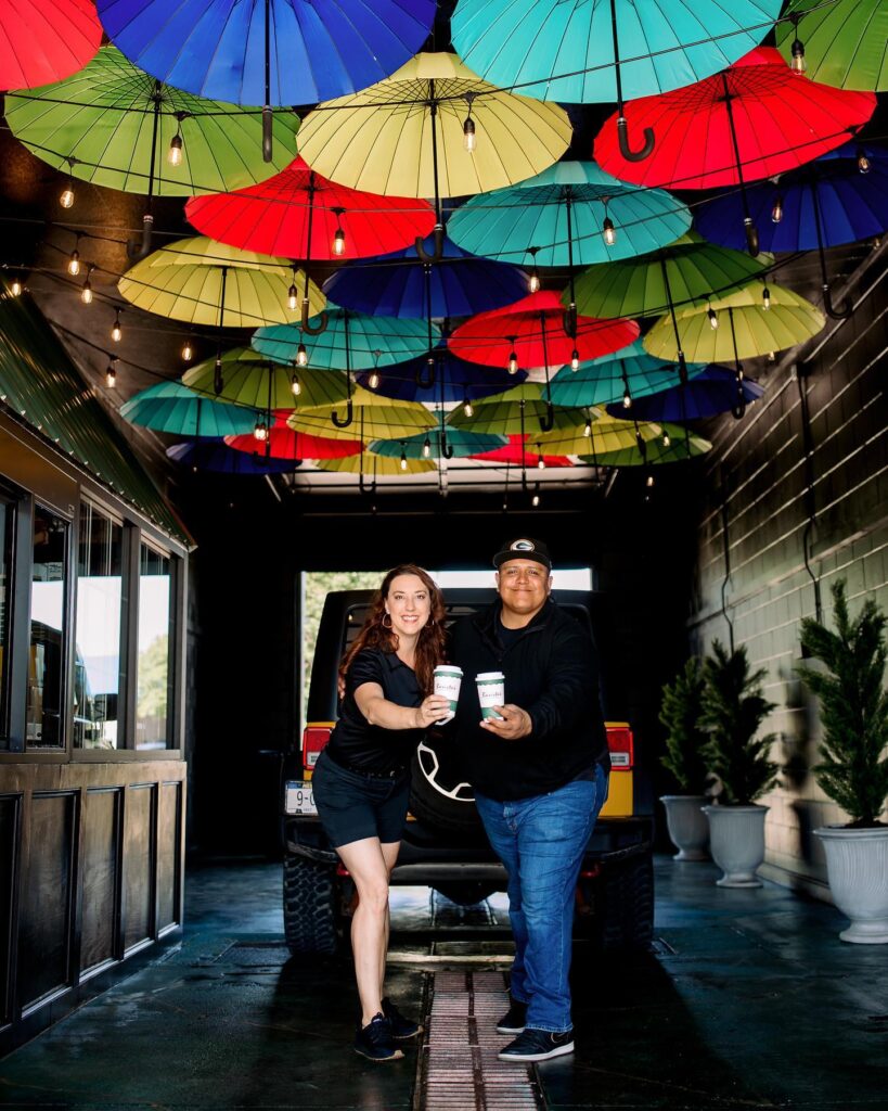two people smiling while holding coffee cups 
