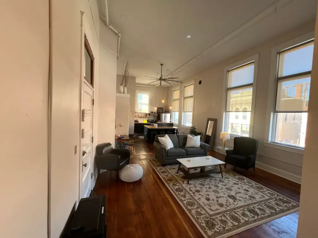 living room with floral area rug, grey couch and two black cushioned seats. 