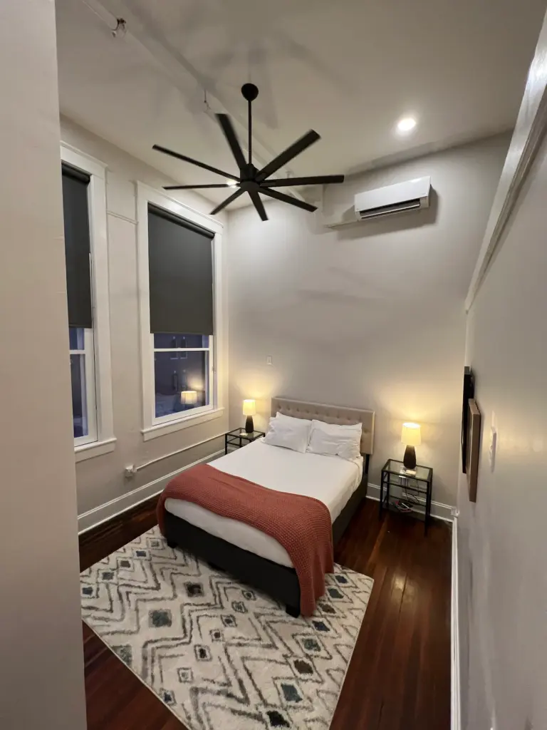 Bedroom with beside tables and lamps at luxury downtown loft #3. Decorative white rug on hardwood flooring. 