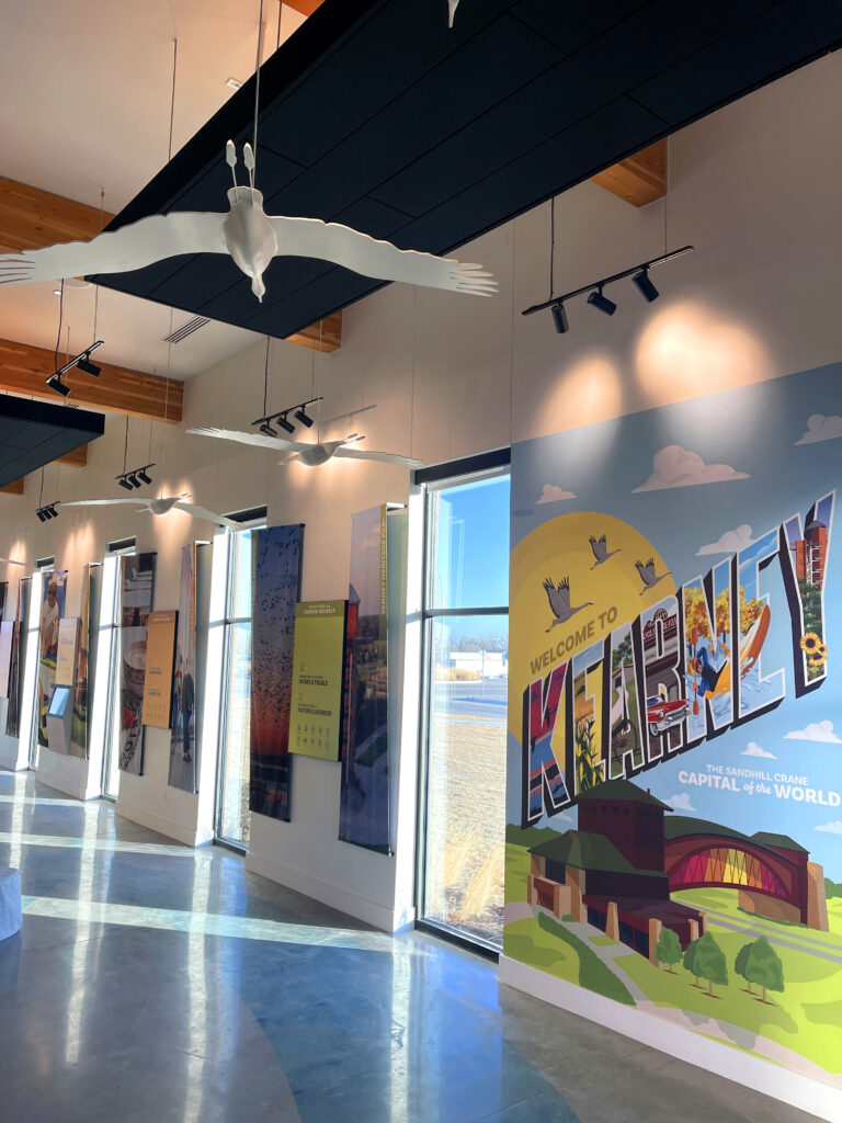 Mural of archway with cranes sculptures hanging from ceiling 