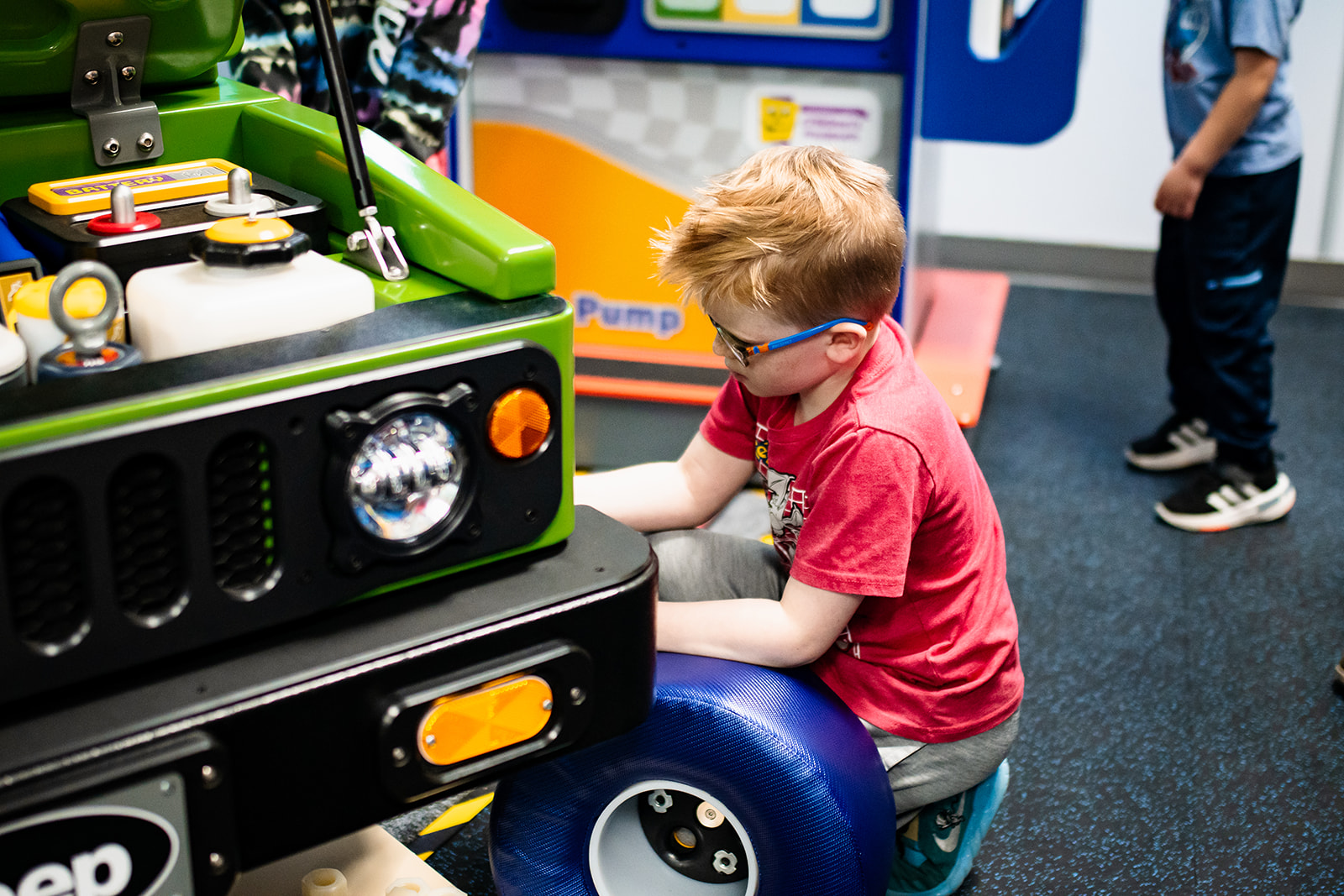 Child working on green toy car at Children's museum.