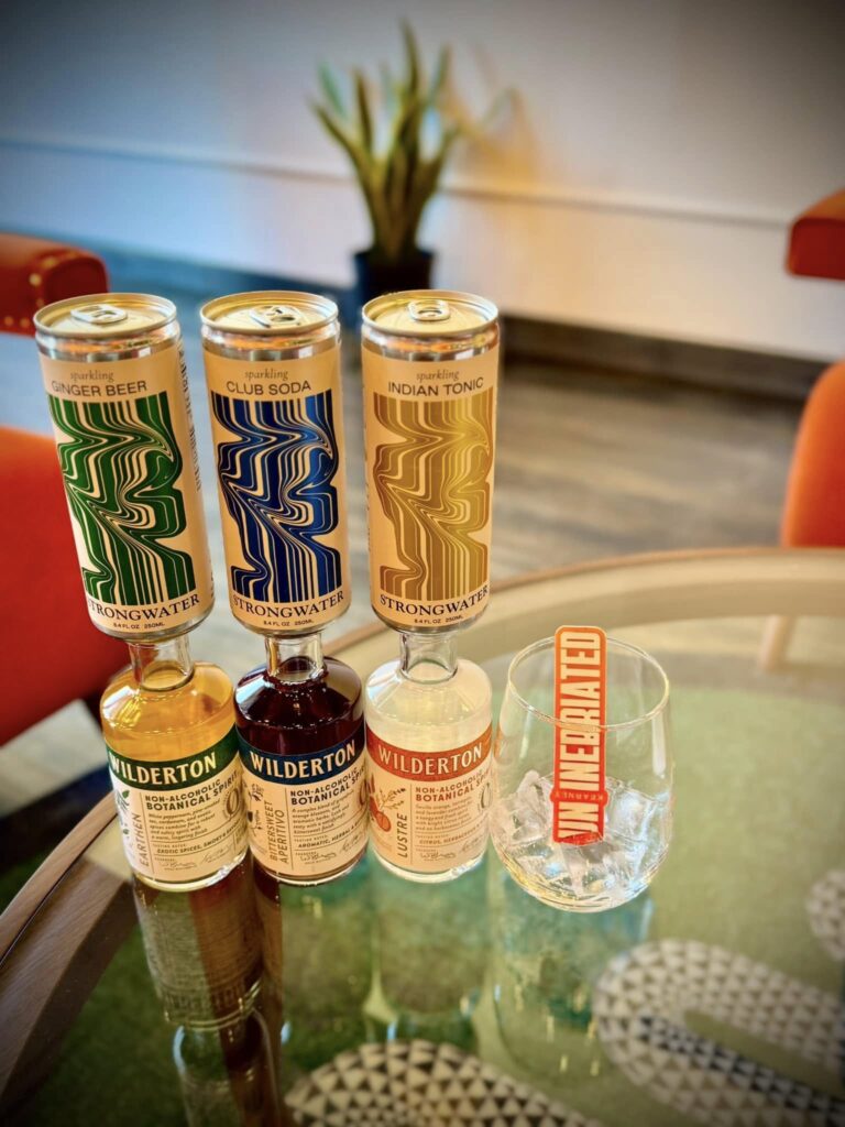 three cans of beer with three bottles of alcohol and a wine glass. 