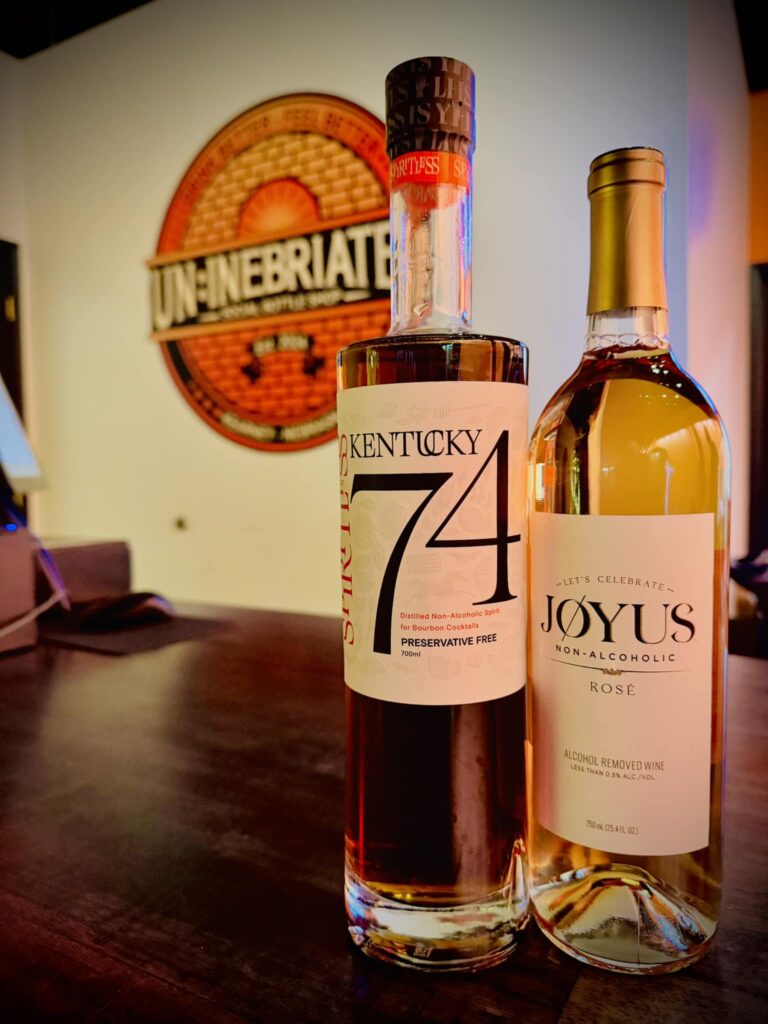 Two bottles of wine with the circular Un:inebriated logo on the wall. 