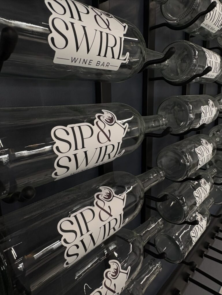 wine rack display of empty sip and swirl labeled wine bottles. 