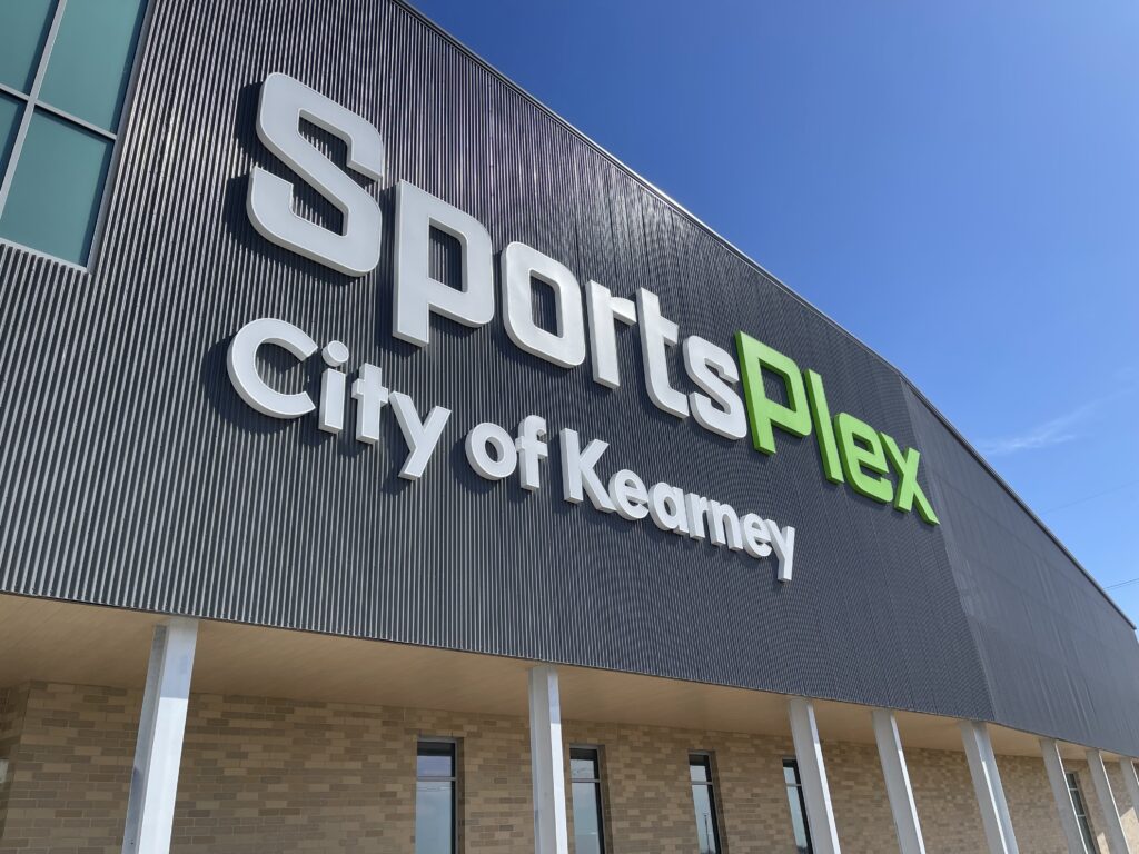 Sign on building with words sports plex city of Kearney written on it.
