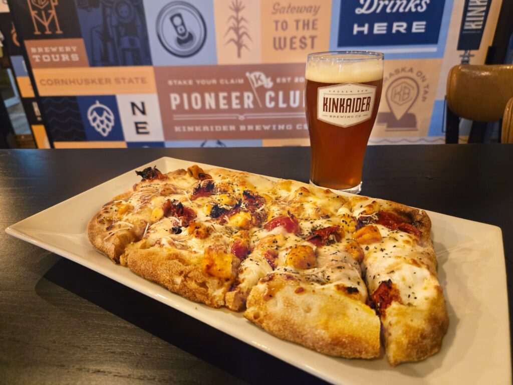 rectangular plate of cheese and tomato pizza with glass of beer. 