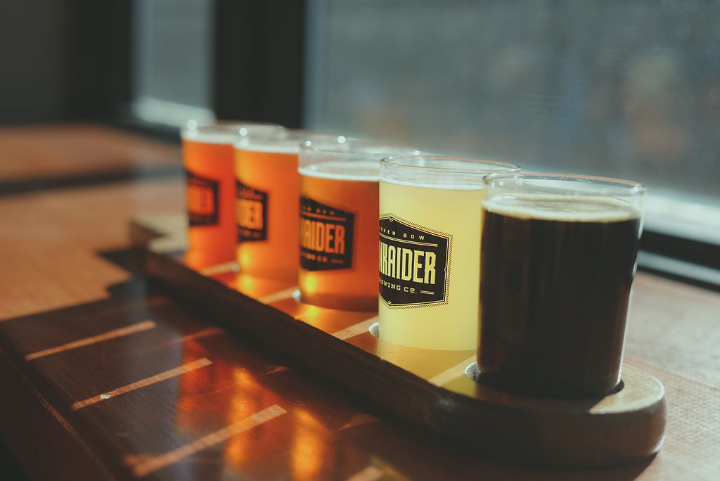 row of red, orange, and yellow colored beer in separate glasses. 