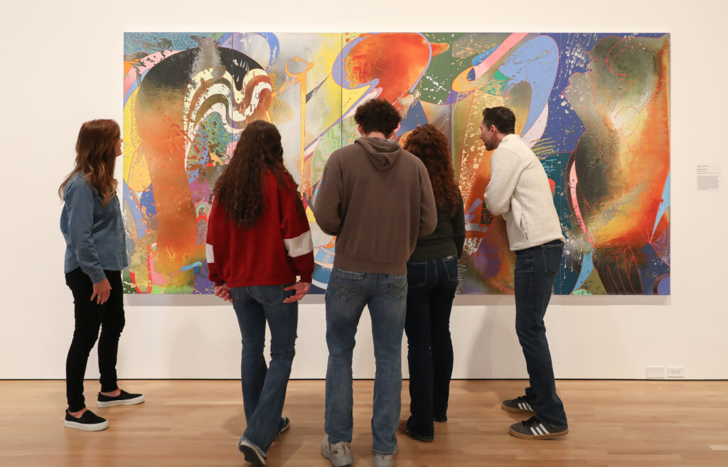 Group of people admiring large abstract painting in museum. 