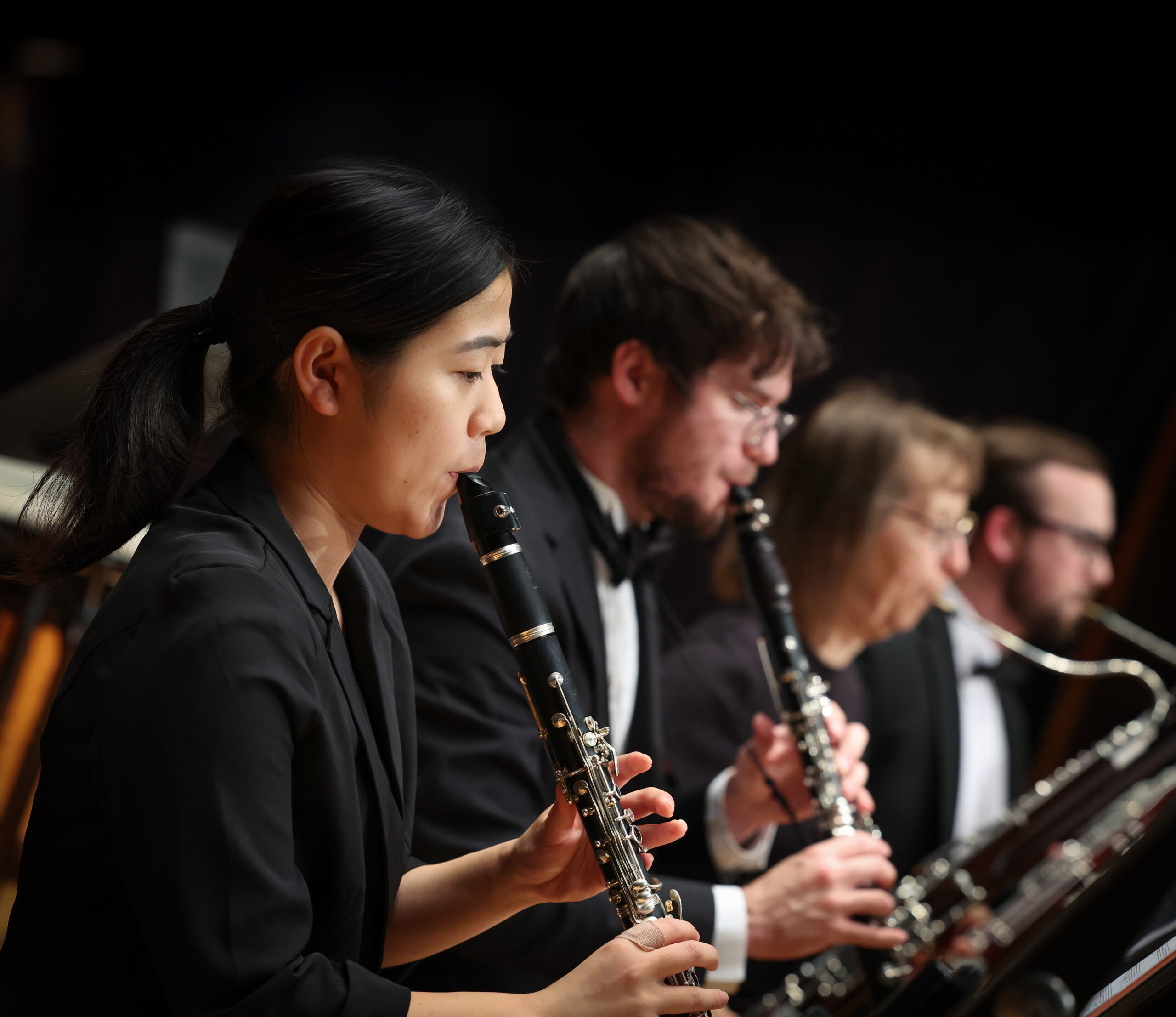 Musicians from the Kearney Symphony Orchestra play clarinets together on stage during a concert performance.